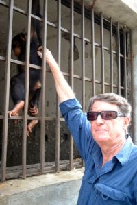 Jacksy, renamed Sweatpea, receives a back-scratch from the PEGAS manager in her bleak, filthy cage before rescue. (Photo: P. McKinney)